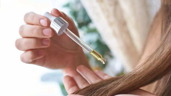Woman applying hair serum to freshly washed hair
